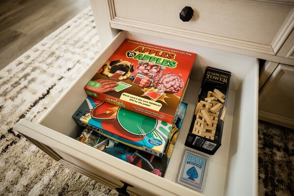 A drawer containing a game called "Apples to Apples," a "Jumbling Tower" puzzle, and a "Jumble" card game.