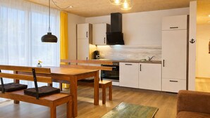 Eine moderne Küche mit Holzschränken, einer schwarzen Dunstabzugshaube und einem Essbereich mit einem Holztisch und Bänken.