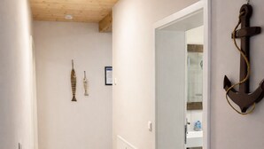 Ein Flur mit Holzboden, einer weißen Tür zu einem Badezimmer und dekorativen Elementen an der Wand.