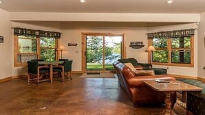 A spacious living room with a large window, a fireplace, and a dining area. - Fischer's Paradise (Presque Isle)