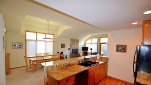 Una cocina amplia con armarios de madera, encimeras de granito y un comedor con mesa y sillas.