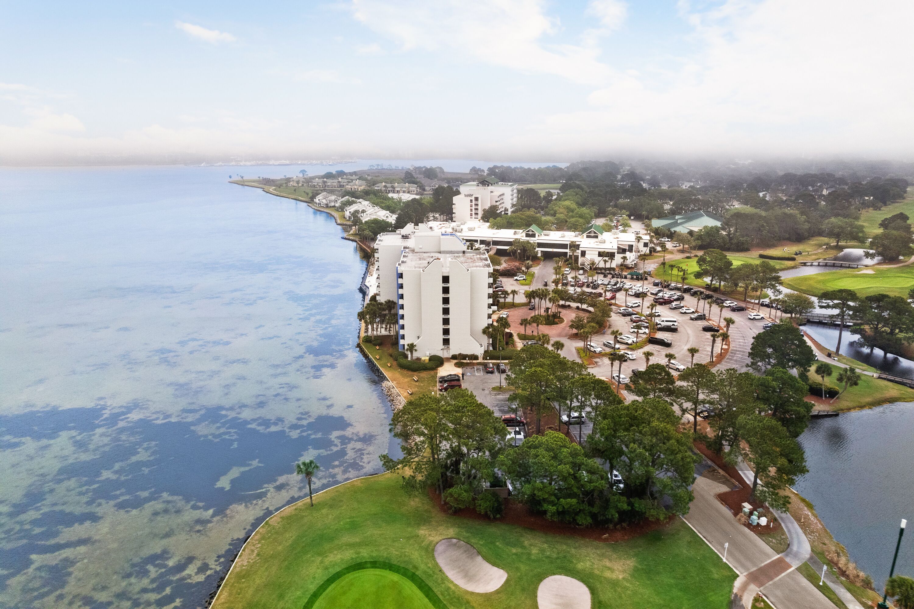 Ett flygbildsfoto av ett hotellkomplex vid kusten, bestående av flera byggnader, en golfbana och en småbåtshamn.