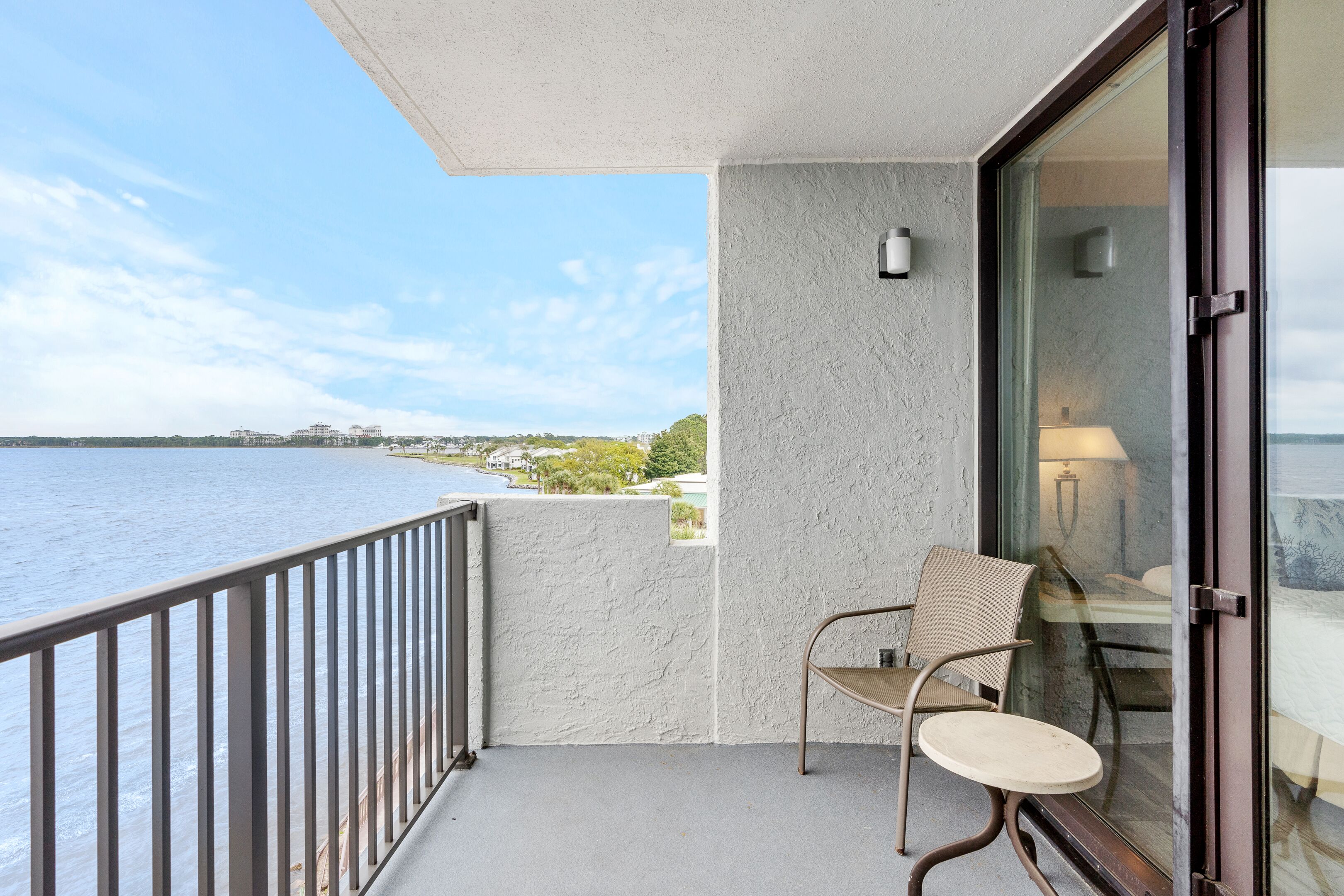 Ein Balkon mit Blick auf das Wasser, einem Stuhl und einem Tisch.