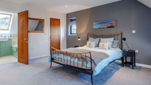 Une chambre à coucher comprenant un lit, une table de chevet, une fenêtre avec vue, une porte et une salle de bain avec un lavabo vert.