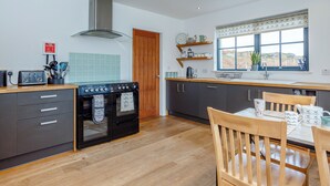 Une cuisine moderne dotée d’un four encastré, d’une cuisinière, de meubles en bois et d’une fenêtre offrant une vue agréable.