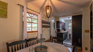 A dining area with a round table, chairs, a hanging light fixture, and a view into the kitchen. - Sky Laurel Cottage - 3 bed 2 bath  home, 1 mile Walk to Blowing Rock, pet friendly (Blowing Rock)