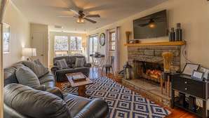 A living room with a fireplace, leather sofas, a coffee table, and a TV mounted above the fireplace. - Sky Laurel Cottage - 3 bed 2 bath  home, 1 mile Walk to Blowing Rock, pet friendly (Blowing Rock)