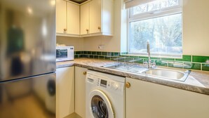 Une cuisine compacte équipée d’un lave-linge intégré, d’un four à micro-ondes et d’un évier.