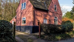 Une maison en briques rouges, dotée d’un toit à forte pente et d’une cheminée.
