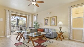 A spacious living room with a ceiling fan, a sofa, a coffee table, and a dining area. - Blue Jay Villa - Vacation Home Near Disney (Davenport)