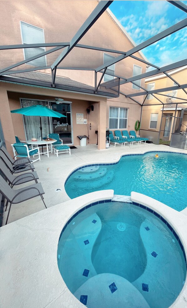 Un espace piscine doté d’un jacuzzi, de chaises longues et d’un patio couvert.