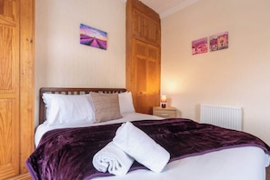 A hotel room with a bed, a nightstand, a lamp, and a radiator. - Thy Grace 3 Bedroom 2 Shower Room Central Newland (Kingston upon Hull)