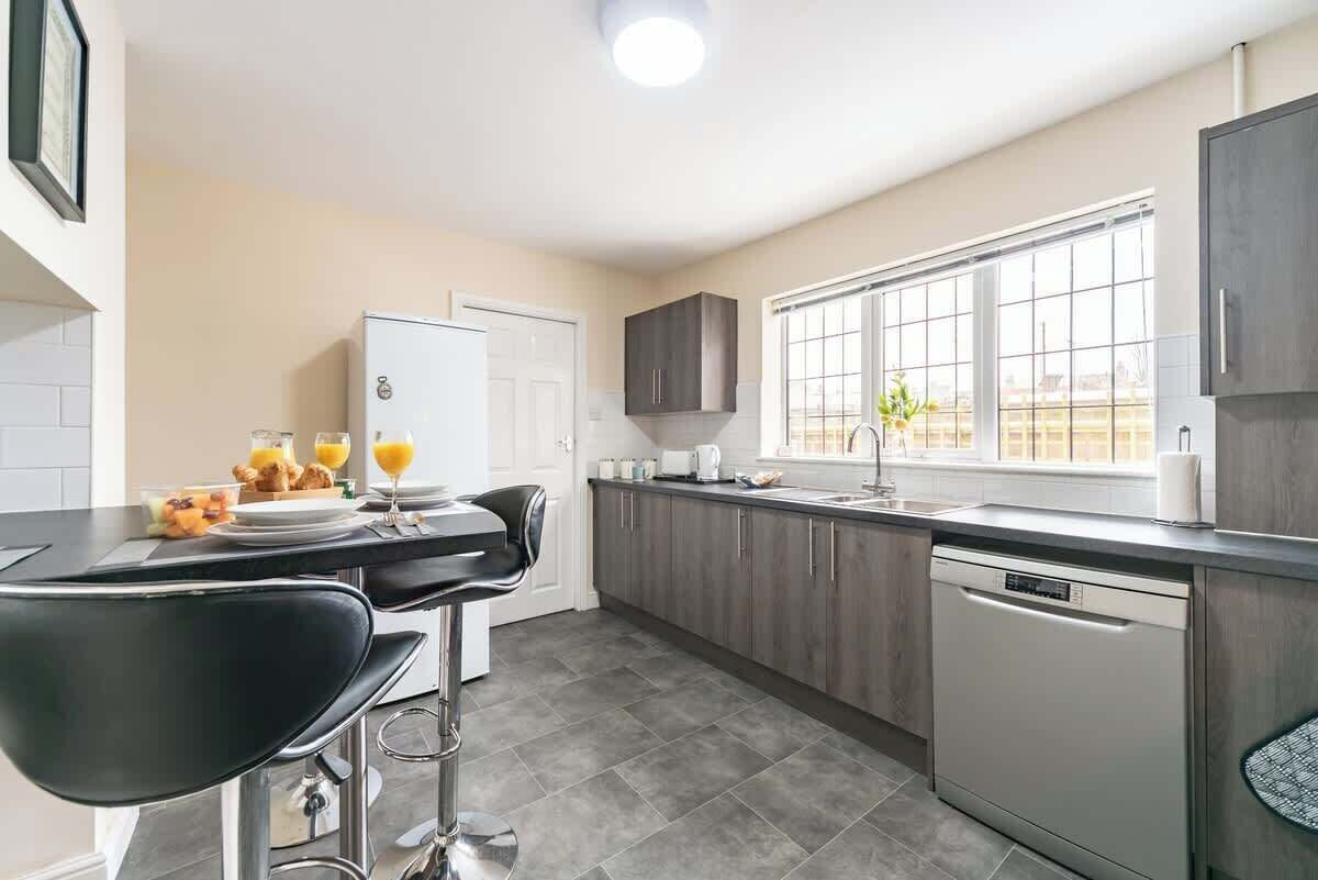 A modern kitchen with a bar area, a dishwasher, and a window with a view.