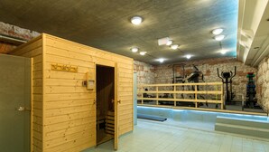 A sauna room with a wooden bench, a bench with a backrest, and a wall-mounted exercise machine. - KrakowRentals - Vanilla 7 Apartment (Kraków)