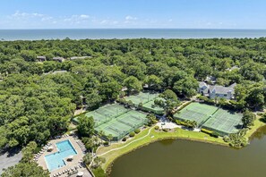A large estate with multiple tennis courts, a swimming pool, and a lake.