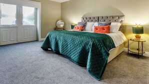 Une chambre à coucher avec un lit, une table de chevet, une lampe, un miroir et une porte.