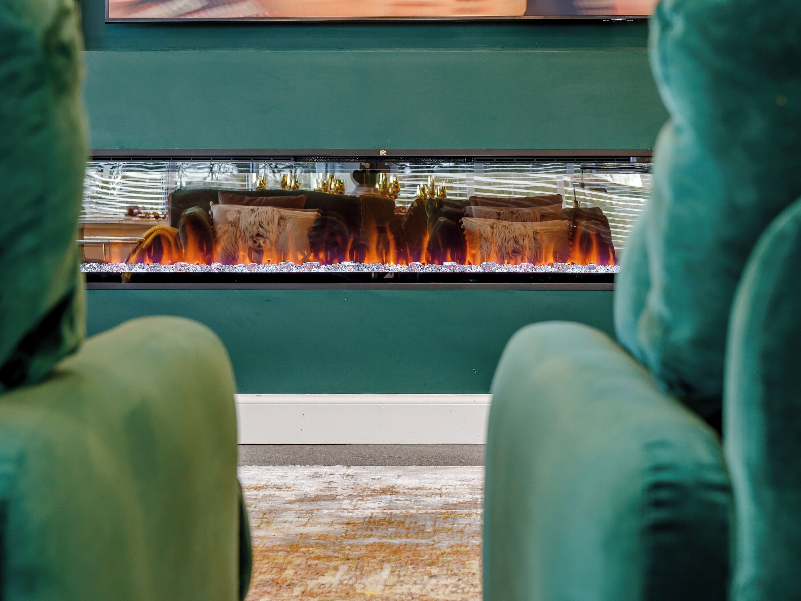 A room with a large aquarium, green walls, and plush green chairs.