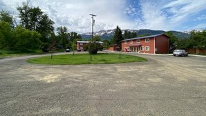Un bâtiment à la façade rouge, un parking et une montagne en arrière-plan.