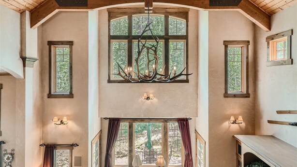 A spacious room with high ceilings, large windows, and a chandelier. - Stunning custom Home w/ private hot tub, quick drive to the slopes! (Keystone)