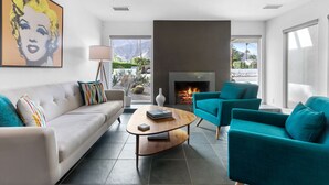 A modern living room with a sofa, teal armchairs, a coffee table, and a fireplace. - Stylish PS Home w/heated pool/spa & mountain views (Palm Springs)