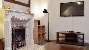 Ein Wohnzimmer mit Kamin, Wandfernseher und einer Holzunterhaltungsecke.
