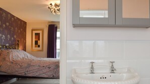 Ein Schlafzimmer mit einem Bett, einem weißen Waschbecken und einem Spiegel darüber.