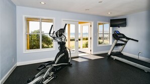 Una palestra attrezzata con un ellittica, un tapis roulant e un televisore.