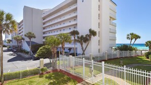 Un hotel a più piani con facciata bianca, palme e vista sull'oceano.