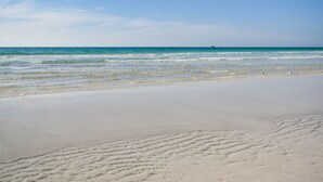 Een strand met heldere lucht en rustig water.