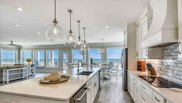 A spacious kitchen with a large island, white cabinetry, and pendant lighting.