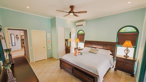 A bedroom with a large bed, two bedside tables with lamps, a ceiling fan, and an air conditioning unit. - 3Br W/ensuite Ba Near Beaches Private Pool&Jacuzzi (Noord)