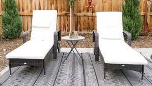Zwei Lounge-Sessel mit weißen Kissen, ein kleiner runder Tisch und eine dekorative Pendelleuchte.
