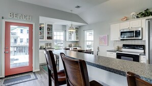 A kitchen with a central island, white cabinets, and a red door labeled "BEACH". - Jamaica Beach Waterfront Home! w/ Paddleboards, Kayak, Pedal Boat, Fishing Gears (Jamaica Beach)