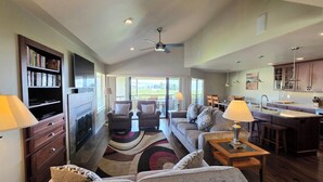 A spacious living room with a fireplace, a large sofa, and a dining area with a view.