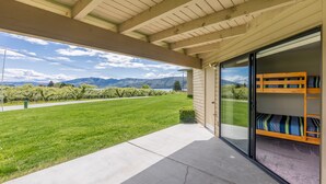 A covered patio with a view of a green lawn and mountains.