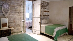 A bedroom with two beds, a wooden wall, a ceiling fan, and a door leading to another room. - Private oceanfront house - lagoon access (Tulum)