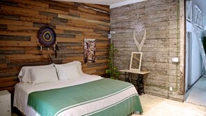 A bedroom with a wooden headboard, a bed with a green and white striped bedspread, a ceiling fan, and a wall-mounted decorative item. - Private oceanfront house - lagoon access (Tulum)