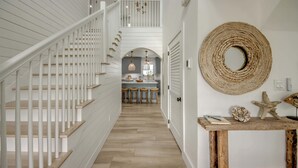A staircase with white railings leading to a second floor, a kitchen area with stools, and a wall-mounted decorative item. - 4969 Estero Modern Pool Home across from Beach (Fort Myers Beach)
