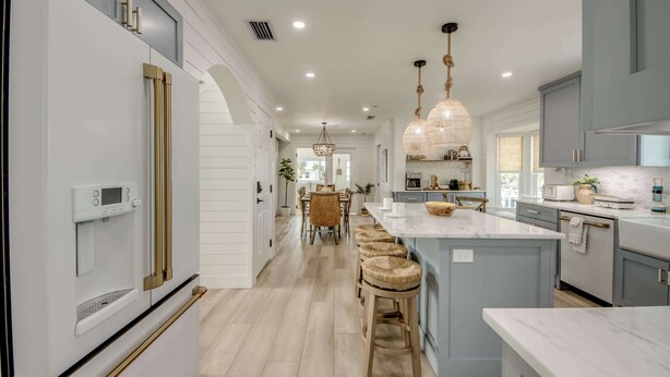 A modern kitchen with a central island, bar stools, pendant lighting, and a dining area with a chandelier. - 4969 Estero Modern Pool Home across from Beach (Fort Myers Beach)
