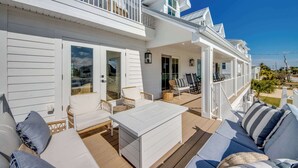 A white two-story house with a covered porch, outdoor furniture, and a view of the ocean. - 4969 Estero Modern Pool Home across from Beach (Fort Myers Beach)