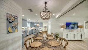 A dining area with a wooden table, woven placemats, and a chandelier. - 4969 Estero Modern Pool Home across from Beach (Fort Myers Beach)