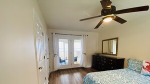 A bedroom with a bed, a dresser, a ceiling fan, and a sliding glass door leading to a balcony. - Your Private Coastal NC Waterfront Escape. Dock, deck, sun, peace, REPEAT! (Aurora)