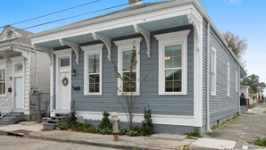 A two-story house with a front porch, a brick chimney, and a small garden with a fire hydrant. - Home near Superdome and 10 minute drive to French Quarter. (New Orleans)