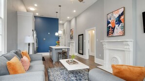 A modern living room with a grey sofa, blue accent wall, and a fireplace. - Home near Superdome and 10 minute drive to French Quarter. (New Orleans)