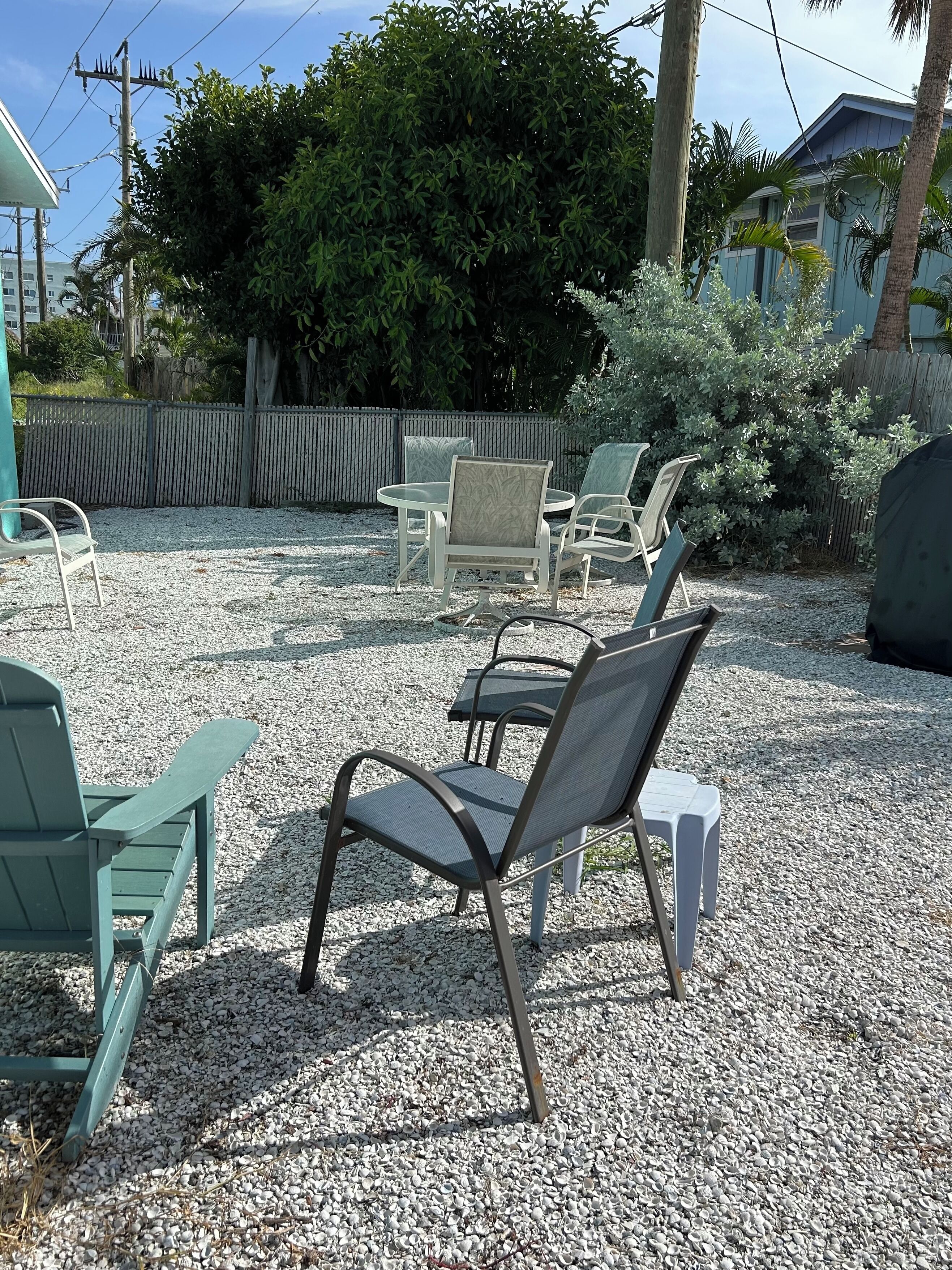 Ein Sitzbereich im Freien mit Stühlen und einem Tisch, umgeben von Kies und Pflanzen.