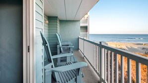 Een balkon met Adirondack-stoelen met uitzicht op een strand.