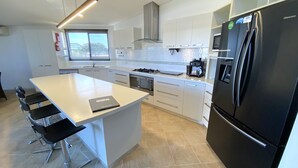 A modern kitchen with a central island, stainless steel appliances, and a view to the outside. - 2 Corella Court - Private Jetty for a boat up to 12mt. (EXMOUTH)