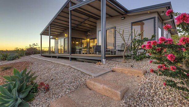 A modern house with a covered patio, outdoor seating, and a gravel driveway. - 2 Corella Court - Private Jetty for a boat up to 12mt. (EXMOUTH)