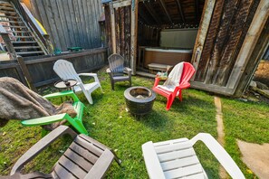 Un patio trasero con un brasero, mobiliario exterior y una terraza de madera.