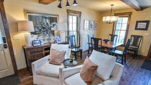 A cozy living room with a fireplace, a dining area, and a kitchen in the background. - Historic Elk Ave 3 Master Suites + Hot Tub - Walk Everywhere (Crested Butte)